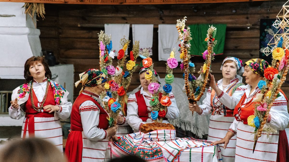 Five women in traditional attire holding vibrant decorations in a cultural celebration.